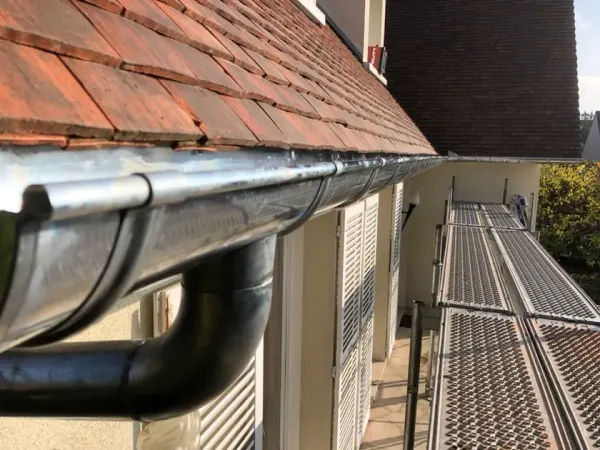 Gouttière et descente en zinc posées sur une toiture en tuiles plates, à Le Mesnil-le-Roi